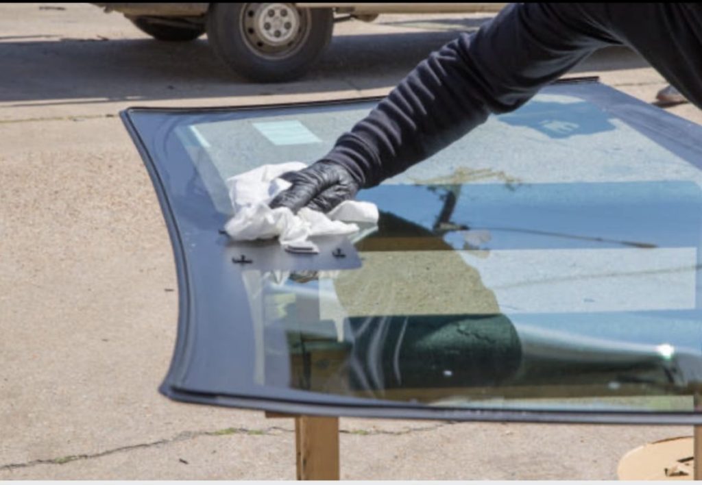 Technician cleaning windshield on glass stand during professional windshield replacement